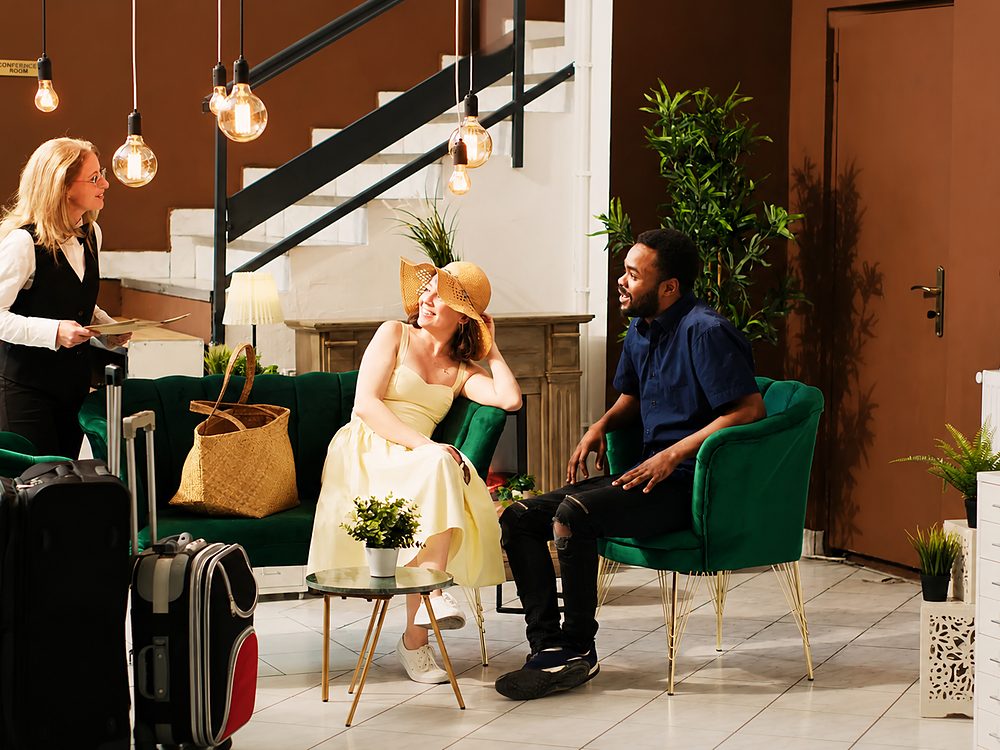 Recepcionista conversando com casal de viajantes em lobby de hotel